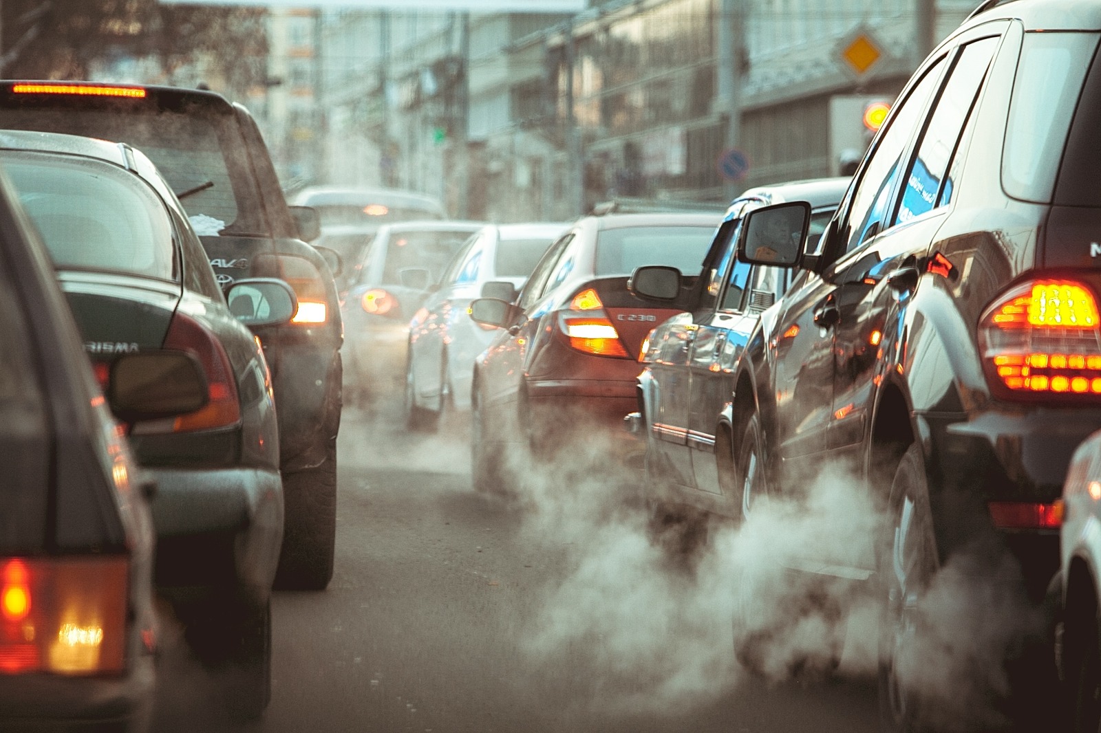 Densidade de tráfego e poluição. Trânsito intenso e carros em fila com fumaça do escapamento remetendo poluição